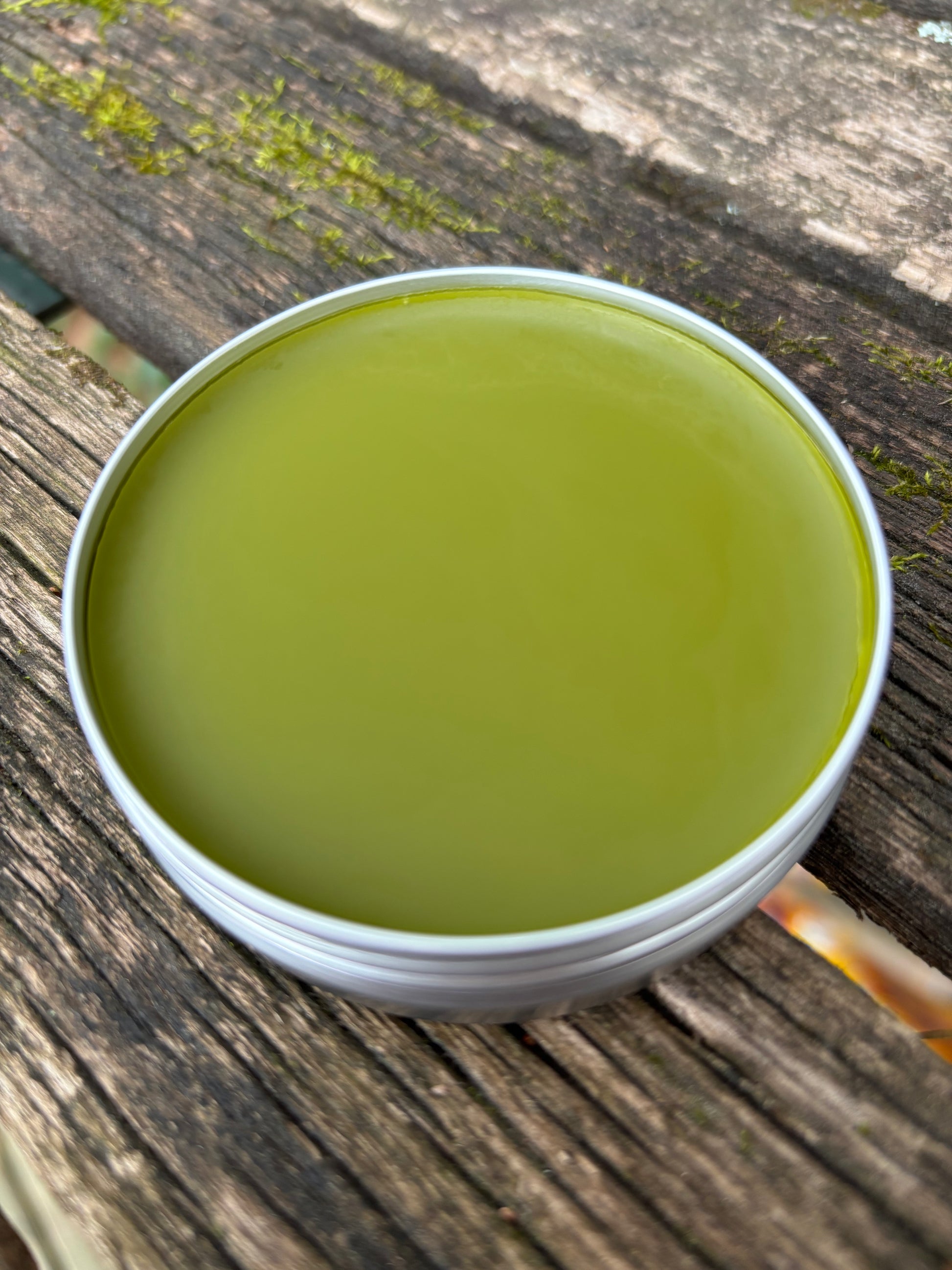 An open two ounce tin of our does-it-all herbal salve for healing wounds, burns, rashes, skin irritation, sores, and more