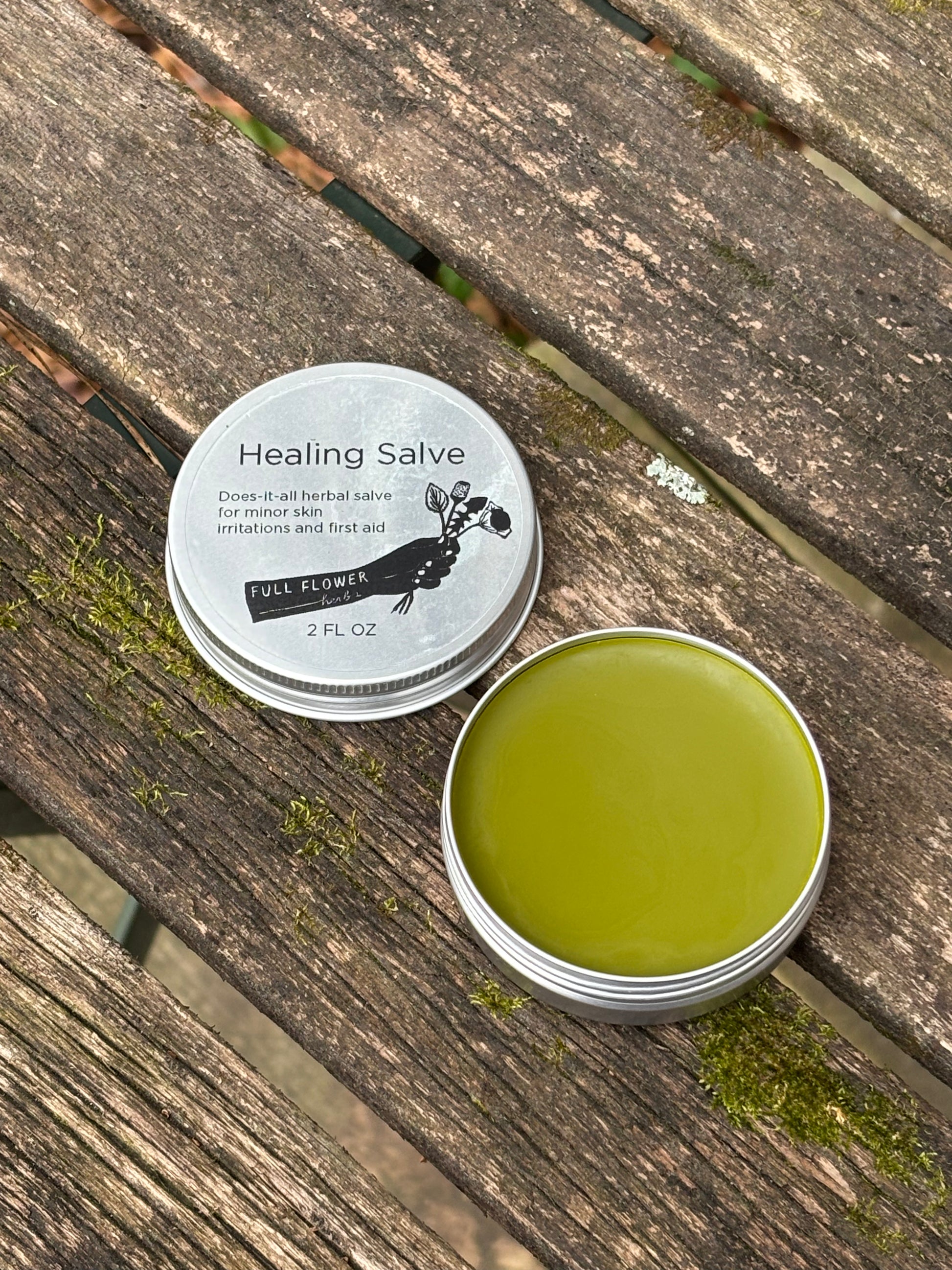 An open two ounce tin of our all purpose herbal salve for healing wounds, burns, rashes, skin irritation, sores, fractures, scars and more